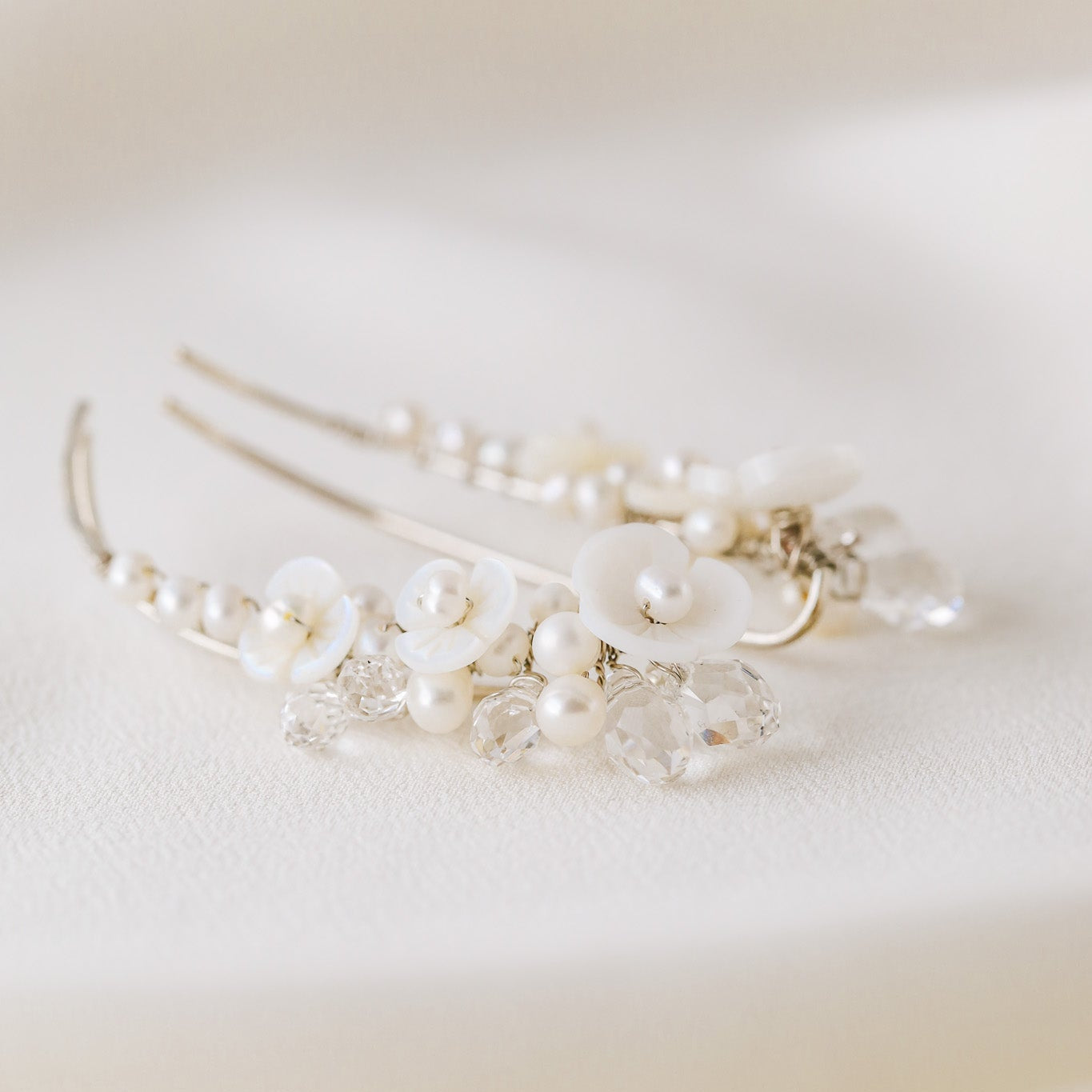 Pair of floral pearl ear climbers displayed on soft white silk background