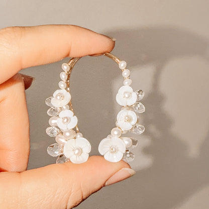 Floral crystal ear climbers held between fingers for size reference