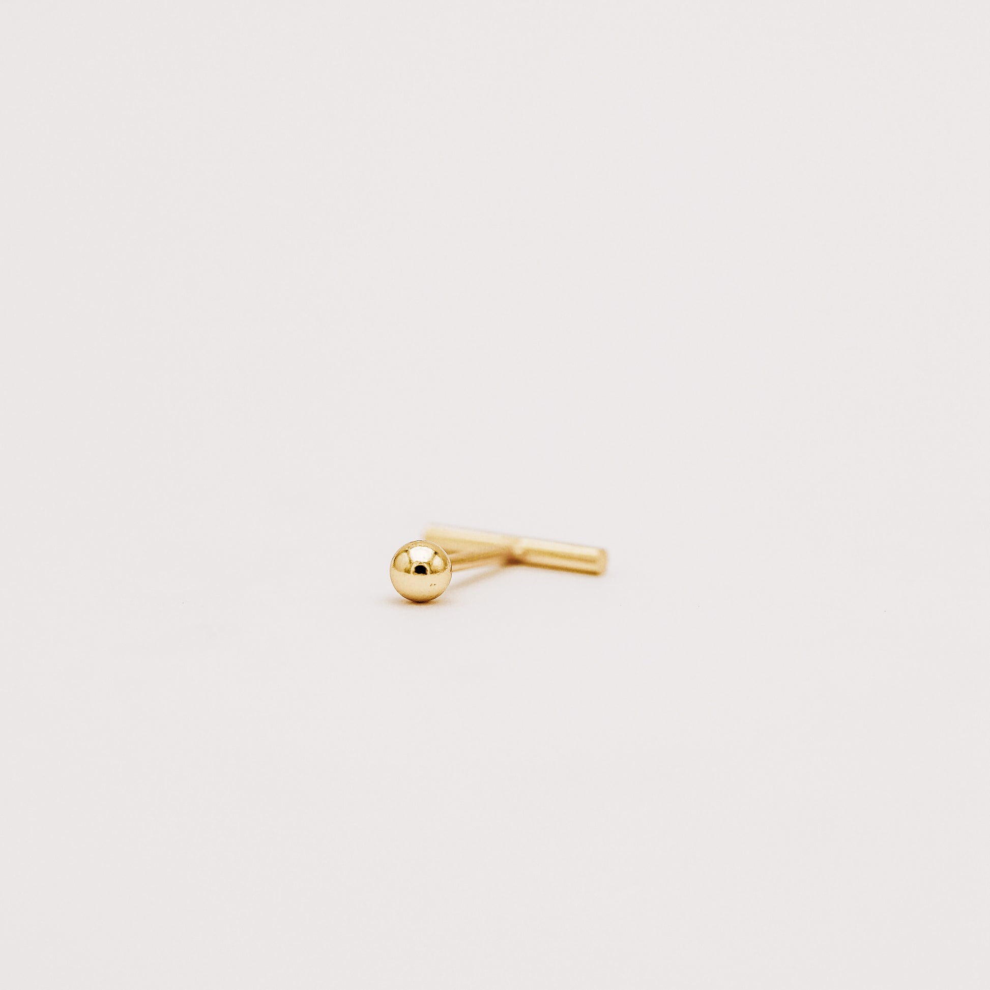 Gold bar earring showing secure screw back closure detail