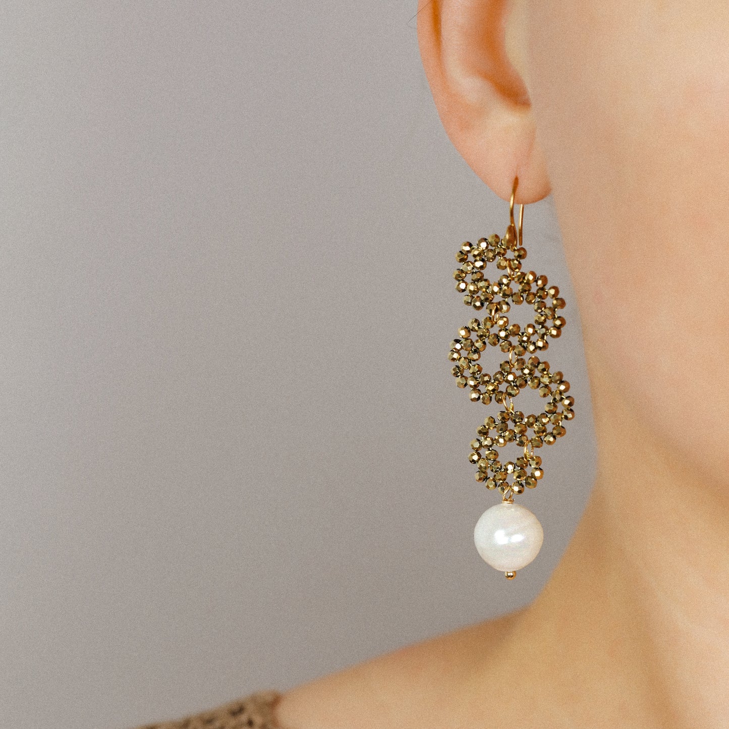 Long gold beaded snake earrings with pearl drop worn on the ear