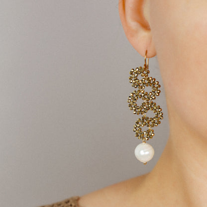 Long gold beaded snake earrings with pearl drop worn on the ear