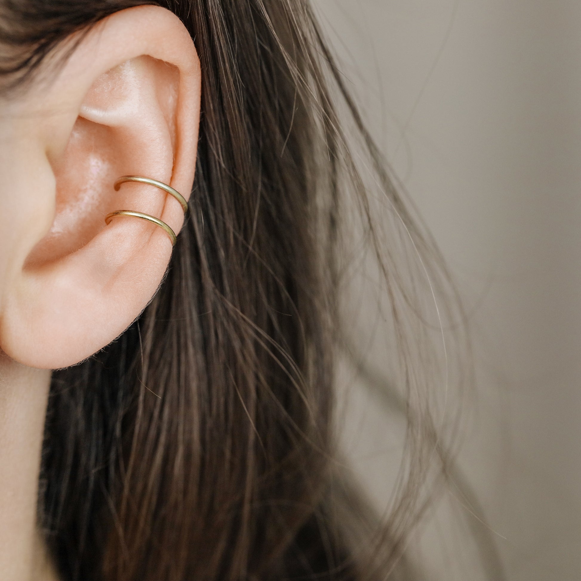 Gold double band ear cuff worn on the upper ear, featuring a slim no piercing design with diamond cut sparkle texture.