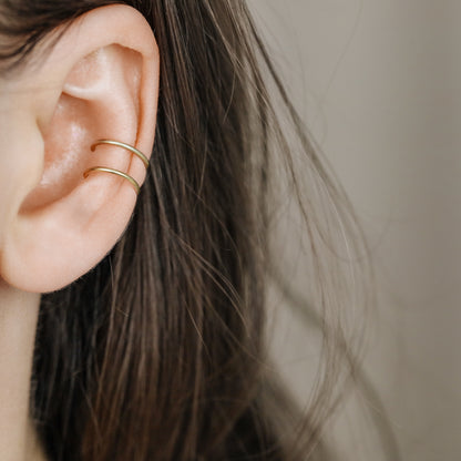 Gold double band ear cuff worn on the upper ear, featuring a slim no piercing design with diamond cut sparkle texture.