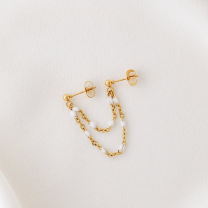 Gold double chain stud earring displayed on white fabric with delicate draped chains