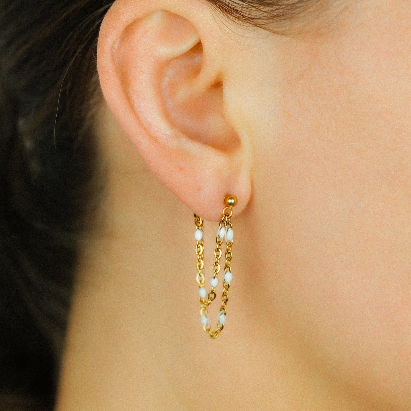 Gold double chain earrings styled on ear with delicate layered chain design