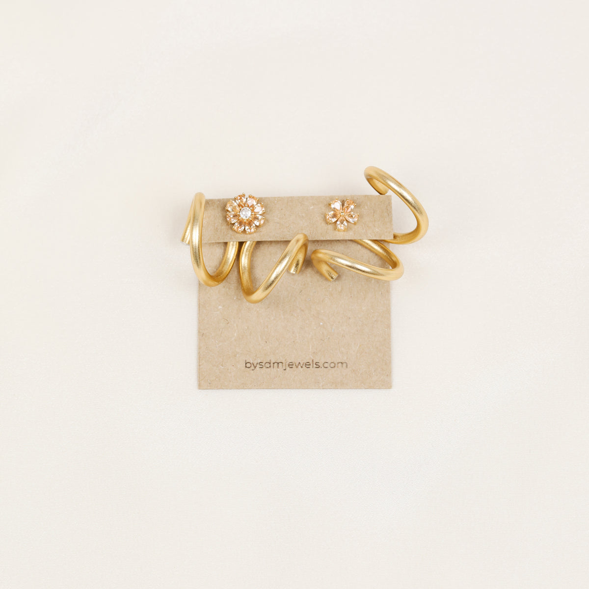 Gold handmade double loop Ear Jacket backs displayed on a jewelry card with decorative floral stud earrings as styling examples.