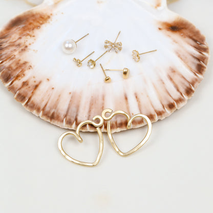 Close-up of two gold hammered aluminum Heart Ear Jackets showing the open heart silhouette, textured handmade surface and small curved top detail.