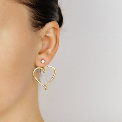 Pair of gold Large Heart Ear Jackets displayed with clear crystal stud earrings, showing the matching pair option and hammered open heart design.