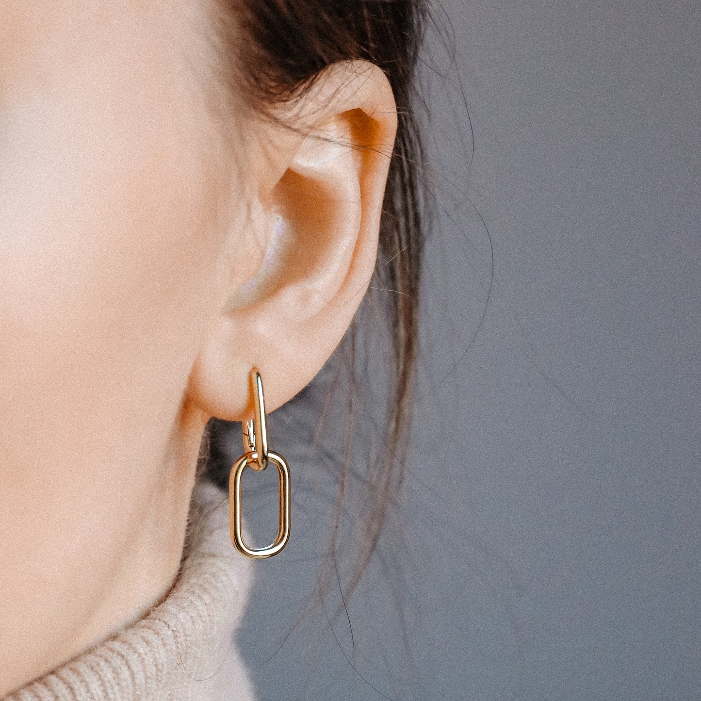 Side view of gold double open-link hinged hoop earring worn on ear