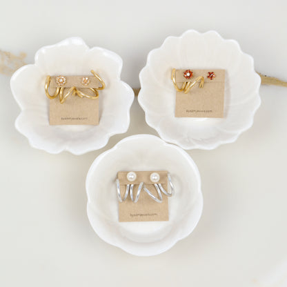 Gold and silver double loop Ear Jackets displayed on jewelry cards with different example studs, showing both available colors and the sculptural wavy design.
