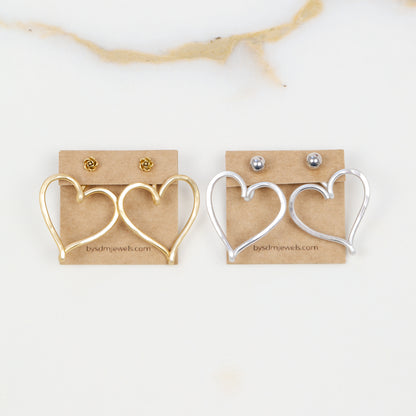Gold and silver Large Heart Ear Jacket pairs displayed side by side with example stud earrings, showing both available colors and the handmade open heart design.