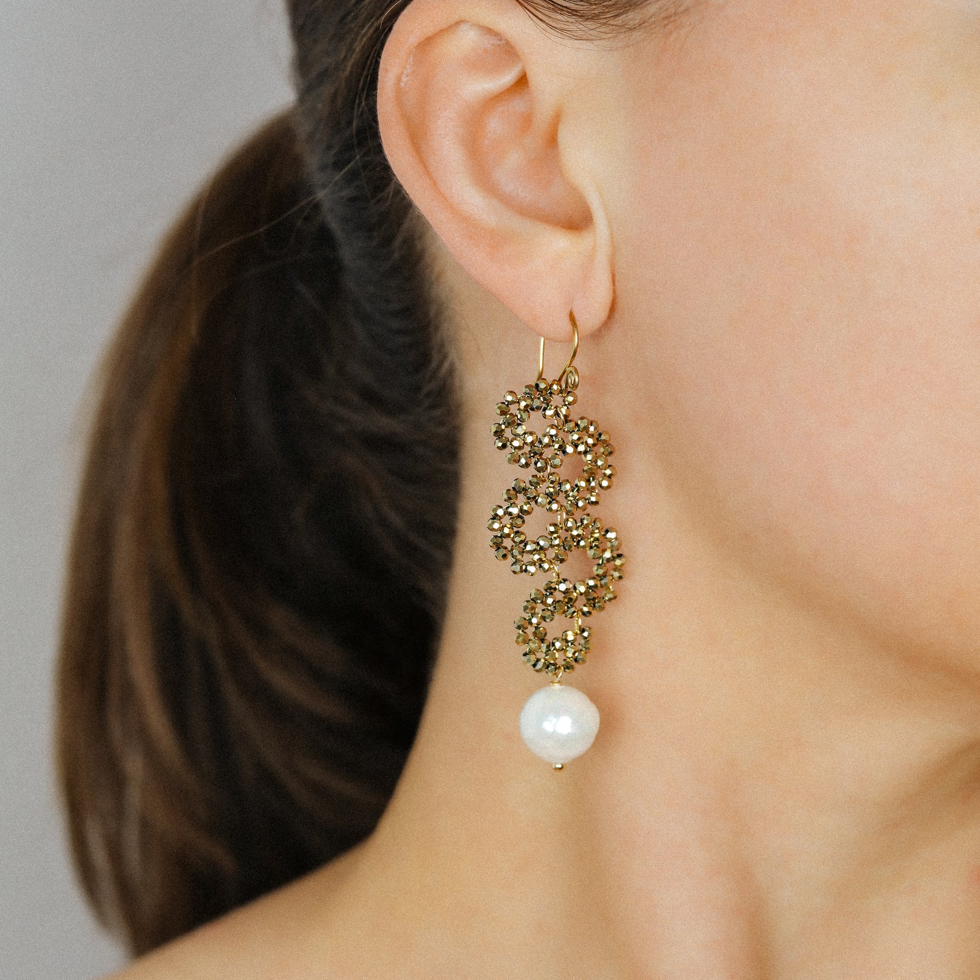 Side view of long gold snake drop earrings with sparkling crystal beads