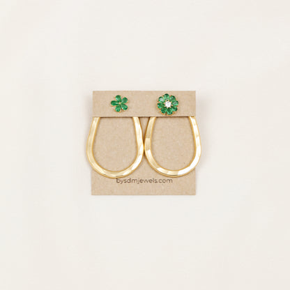 Matching pair of gold hammered teardrop ear jackets displayed with decorative green studs on a jewelry card.