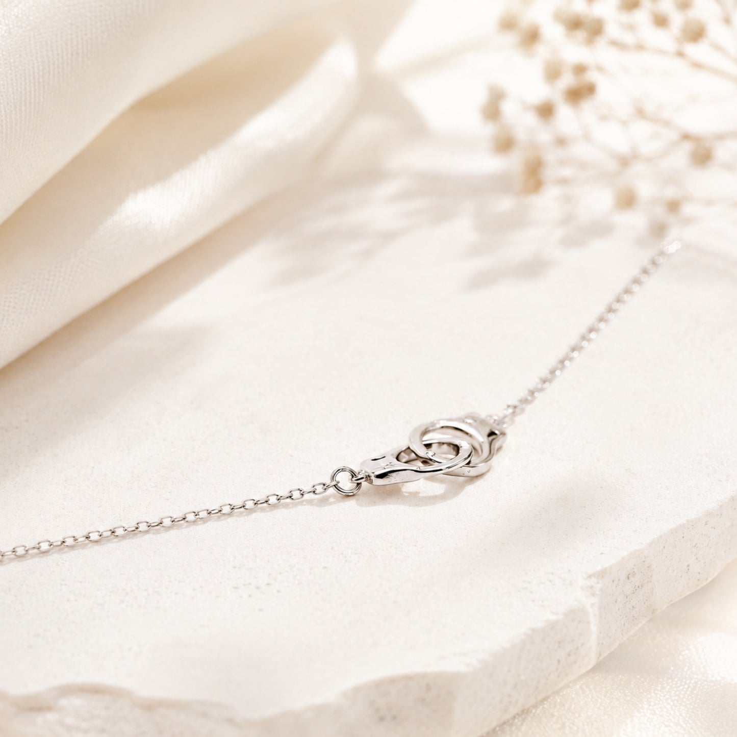 Sterling silver handcuff necklace displayed on light marble surface with soft natural light