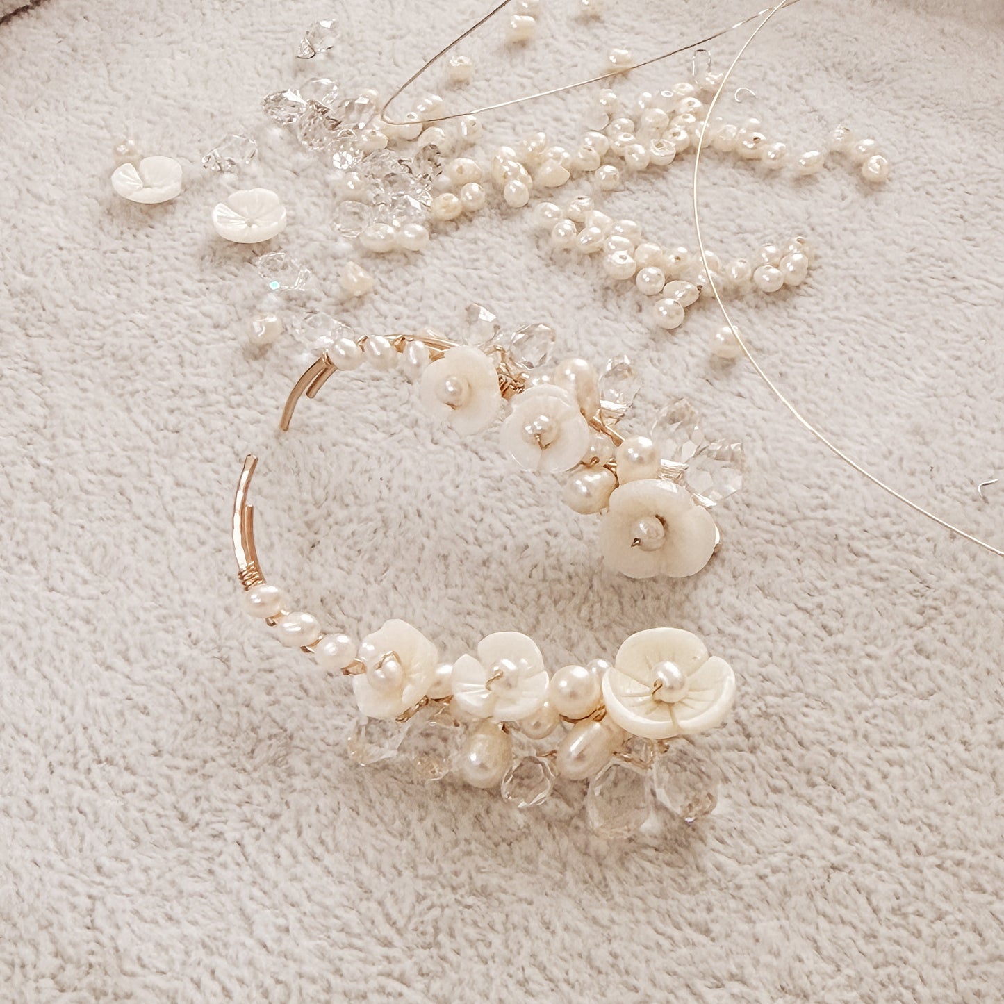 Handmade pearl flower ear climbers displayed on neutral fabric with scattered pearls