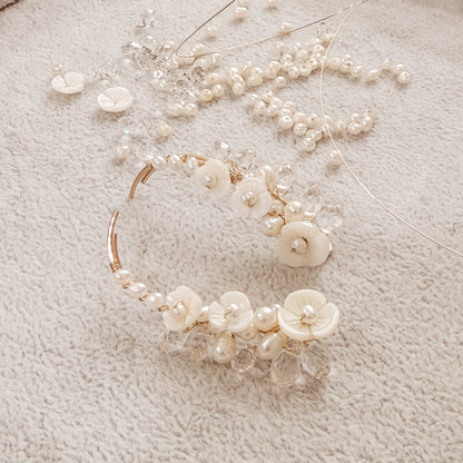 Handmade pearl flower ear climbers displayed on neutral fabric with scattered pearls