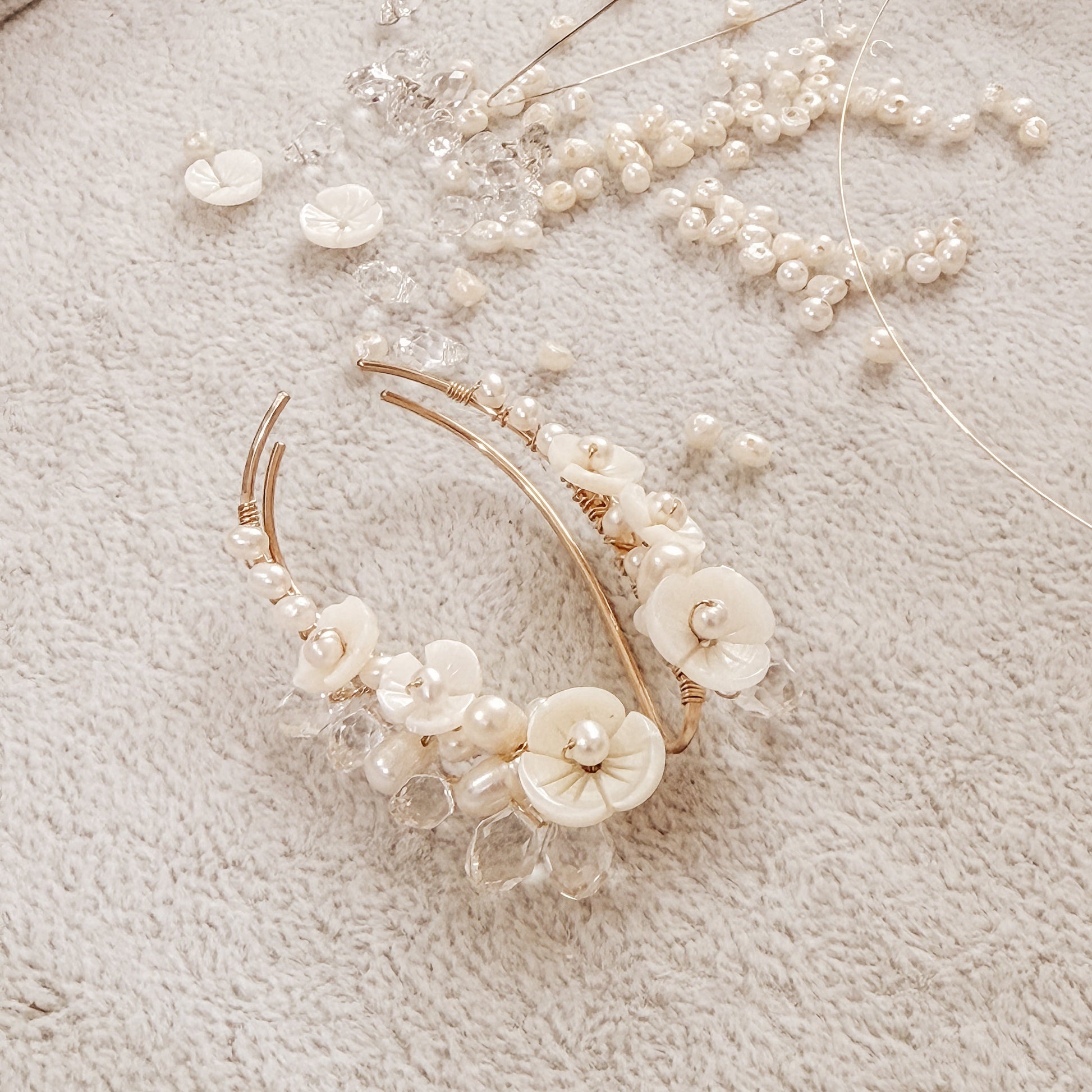 Handmade pearl flower ear climbers displayed on neutral fabric with scattered pearls