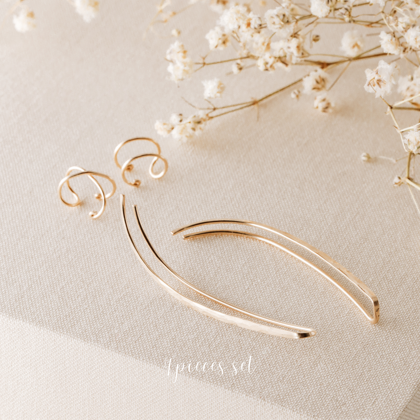 4 pieces ear climber set displayed on beige fabric with dried white flowers, featuring a pair of long hammered ear climbers, one Double Line no-piercing helix cuff and one Criss-Cross no-piercing helix cuff in a warm gold finish.