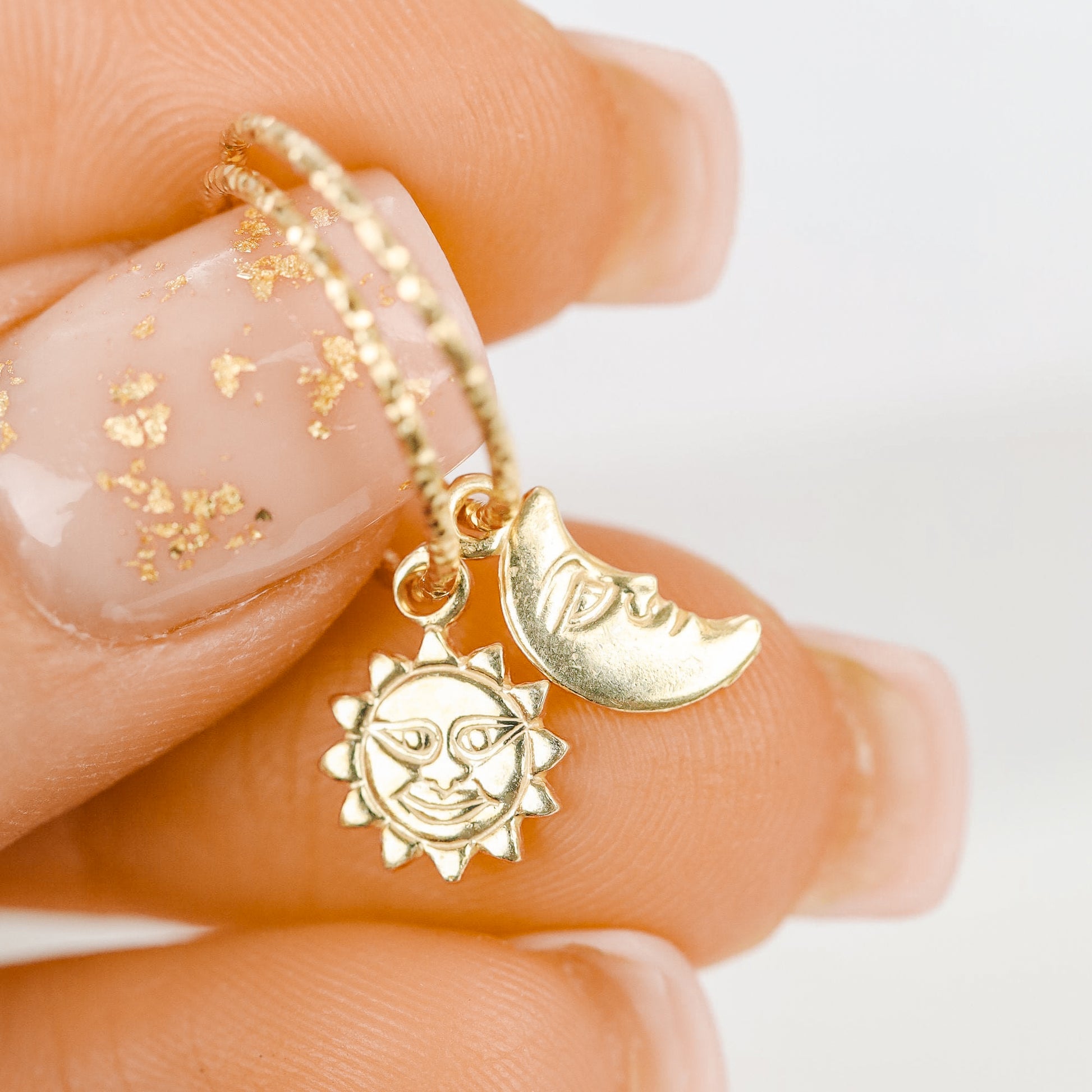 Single 18k yellow gold endless hoop earring featuring a diamond-cut textured finish and a smiling celestial sun charm pendant, shown in a cartilage helix piercing.