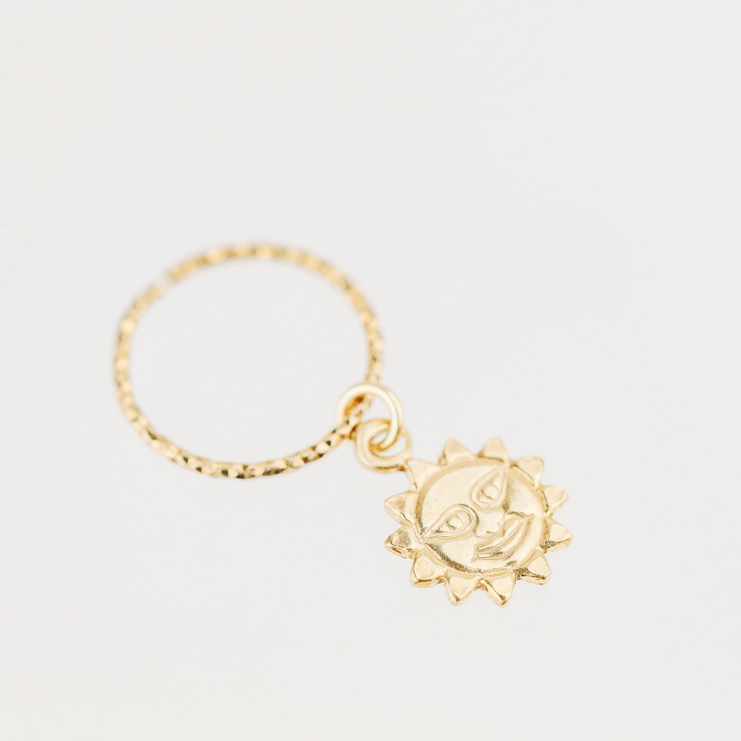High-resolution shot of a single 18k gold plated sun charm hoop earring on a white background.