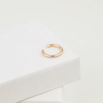 Thick smooth no-piercing ear cuff shown worn on different areas of the ear, including lobe, conch, cartilage and upper helix, with a rounded wrap design available in sterling silver, 18k yellow gold plated sterling silver, 18k rose gold plated sterling silver and black aluminum.