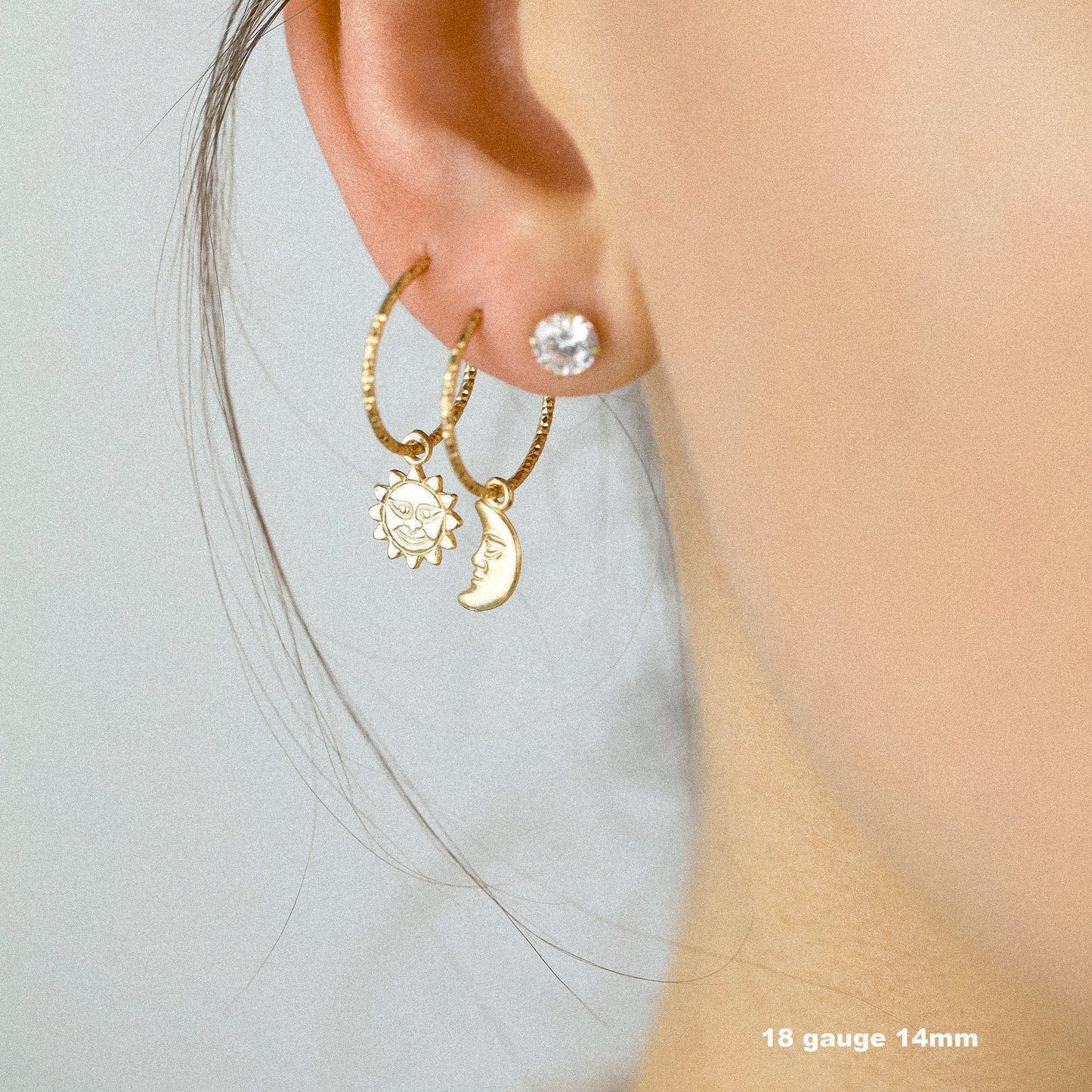 Single 18k yellow gold endless hoop earring featuring a diamond-cut textured finish and a smiling celestial sun charm pendant, shown in a cartilage helix piercing.