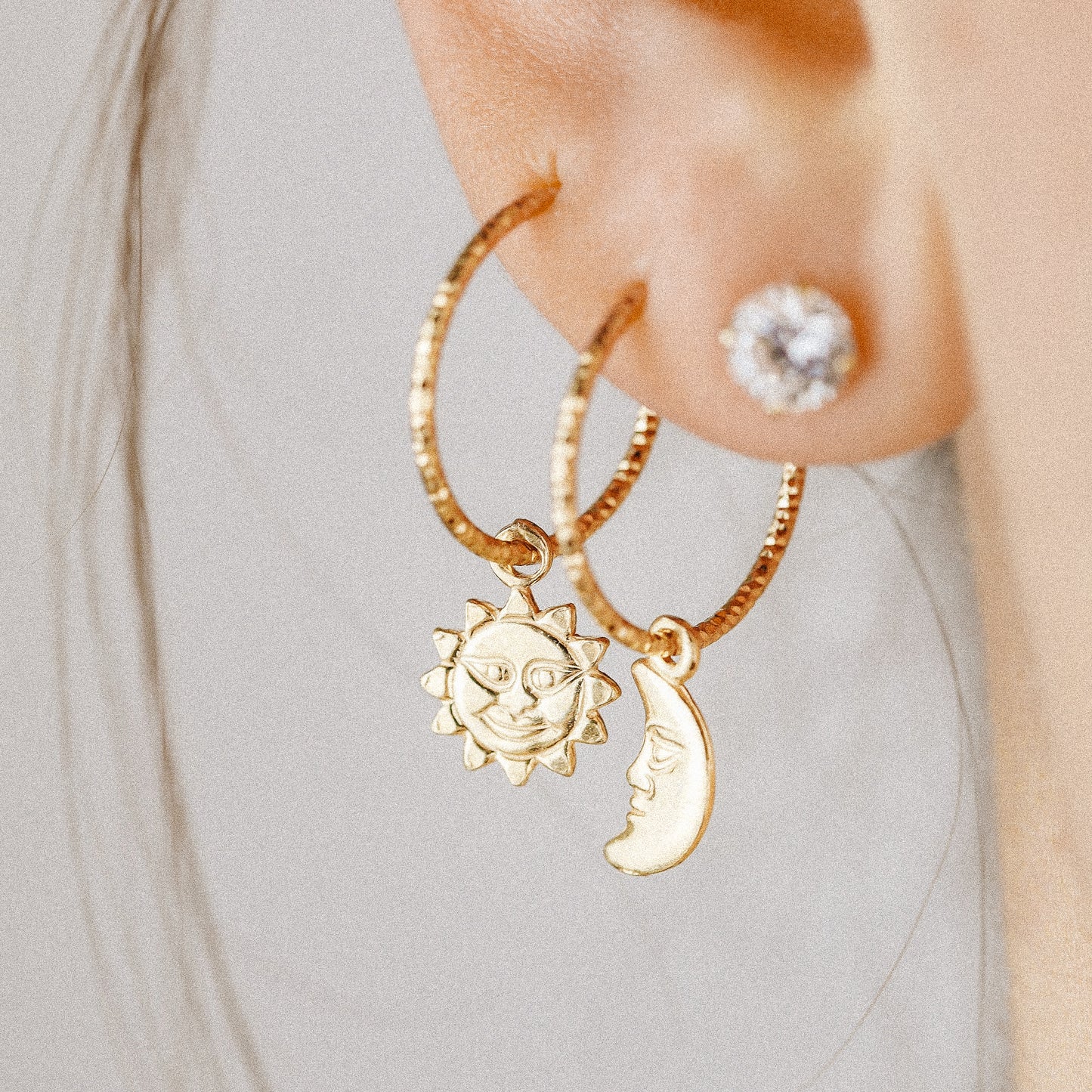 Single 18k yellow gold endless hoop earring featuring a diamond-cut textured finish and a smiling celestial sun charm pendant, shown in a cartilage helix piercing.