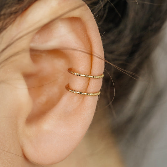 Gold double band ear cuff worn on the upper ear, featuring a slim no piercing design with diamond cut sparkle texture.