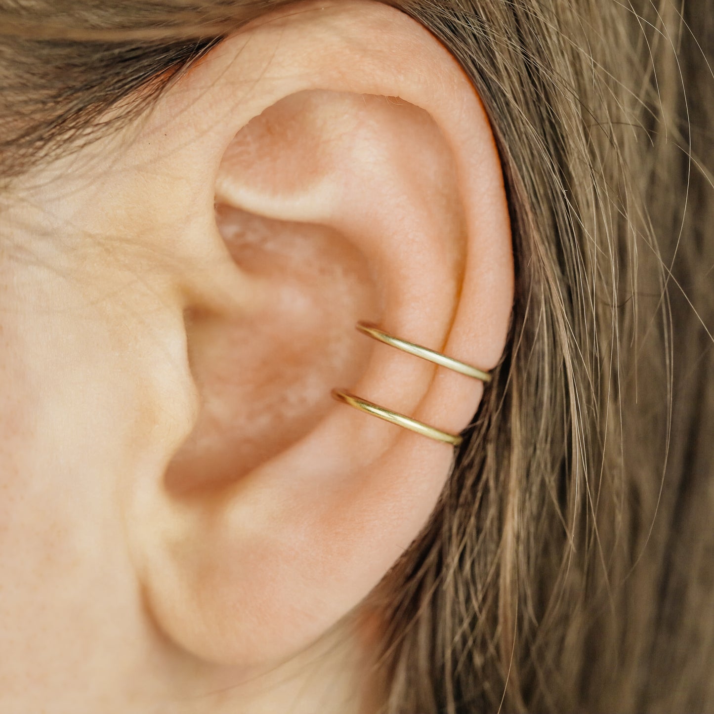 Gold double band ear cuff worn on the upper ear, featuring a slim no piercing design with diamond cut sparkle texture.