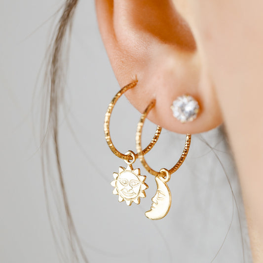 Single 18k yellow gold endless hoop earring featuring a diamond-cut textured finish and a smiling celestial sun charm pendant, shown in a cartilage helix piercing.