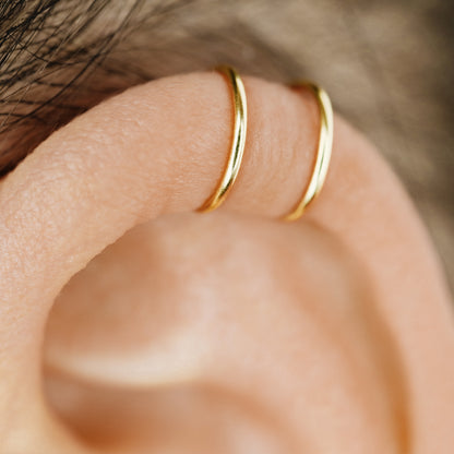 No-piercing double line and criss cross helix ear cuff shown on the upper ear, with smooth and diamond cut finish options for cartilage styling.