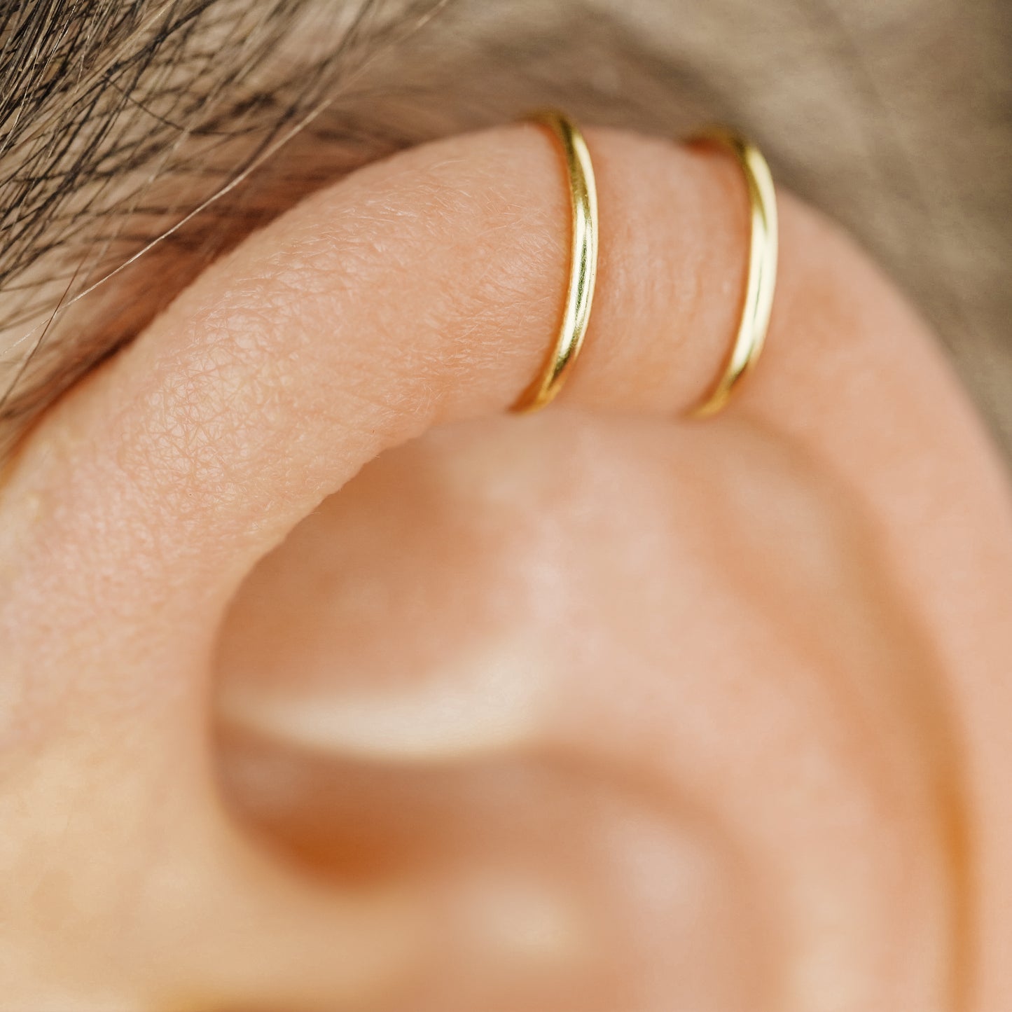 No-piercing double line and criss cross helix ear cuff shown on the upper ear, with smooth and diamond cut finish options for cartilage styling.