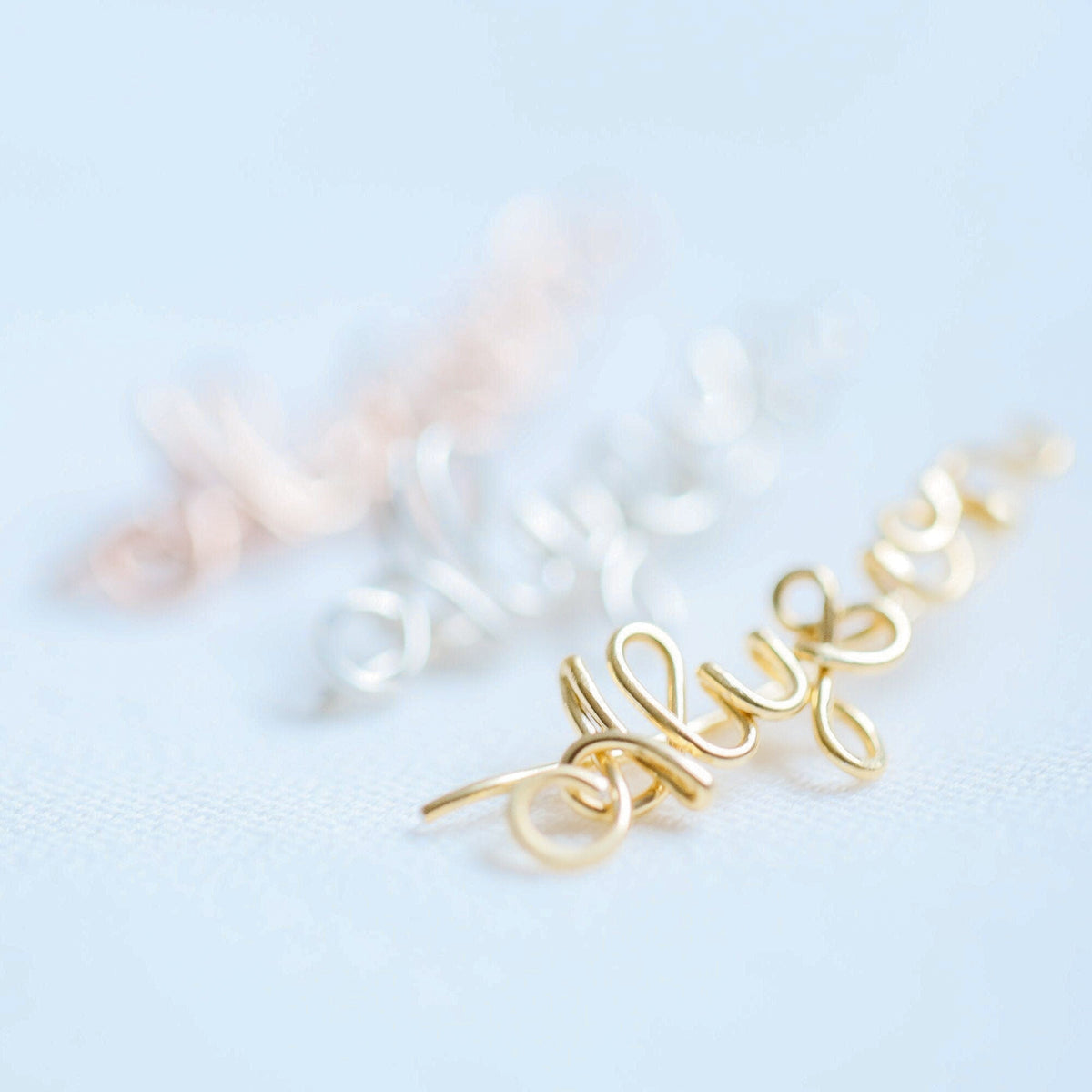 Handmade personalized name ear climber worn across the lobe through one standard piercing, featuring a custom flowing wire script design made with the chosen name or word up to 10 characters, available as a single left ear climber, single right ear climber or pair in solid 925 sterling silver, 14k gold filled and 14k rose gold filled.