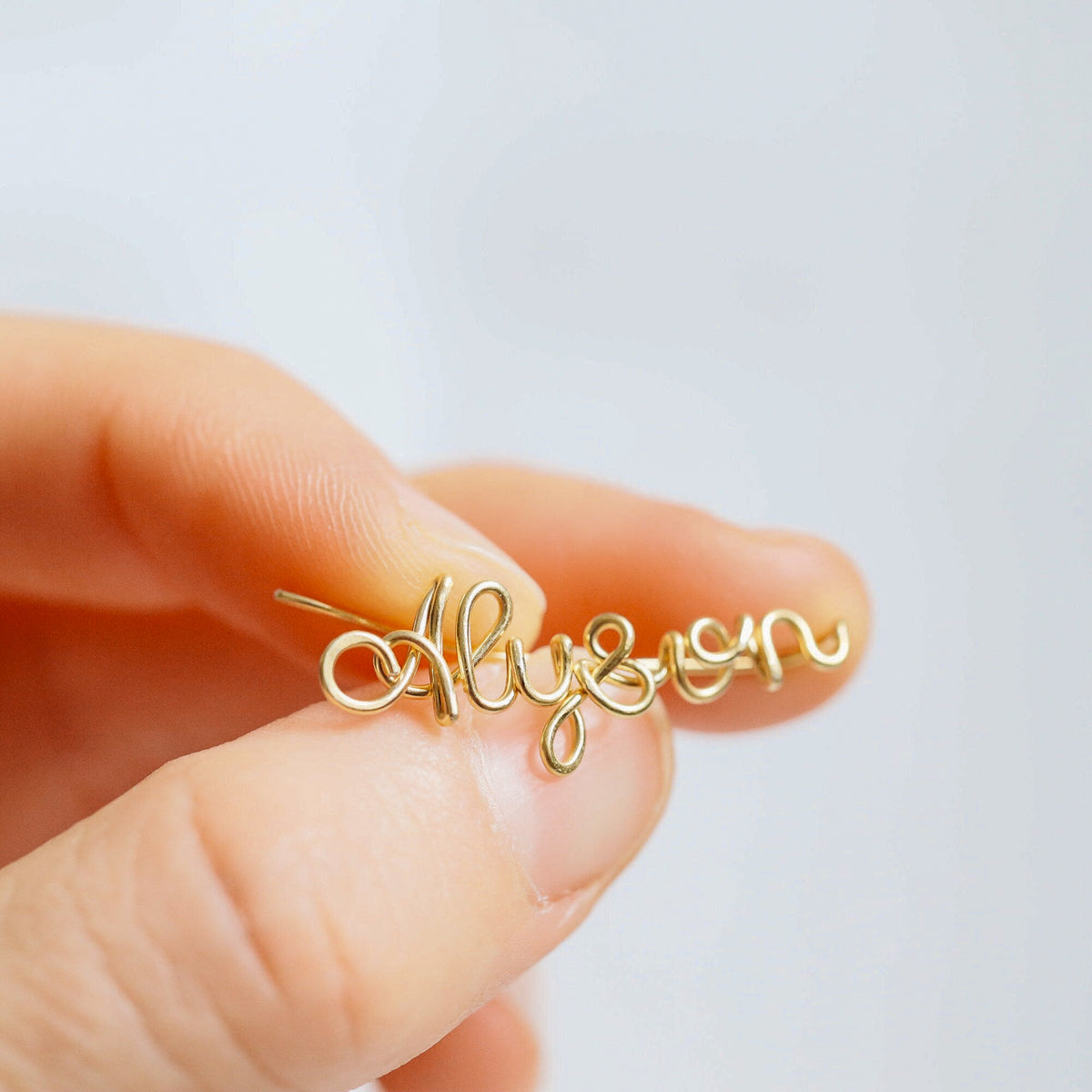 Handmade personalized name ear climber worn across the lobe through one standard piercing, featuring a custom flowing wire script design made with the chosen name or word up to 10 characters, available as a single left ear climber, single right ear climber or pair in solid 925 sterling silver, 14k gold filled and 14k rose gold filled.