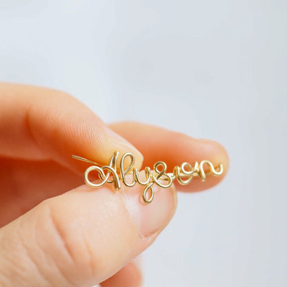 Handmade personalized name ear climber worn across the lobe through one standard piercing, featuring a custom flowing wire script design made with the chosen name or word up to 10 characters, available as a single left ear climber, single right ear climber or pair in solid 925 sterling silver, 14k gold filled and 14k rose gold filled.