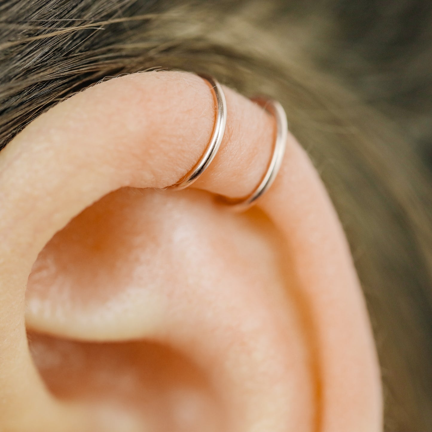 No-piercing double line and criss cross helix ear cuff shown on the upper ear, with smooth and diamond cut finish options for cartilage styling.