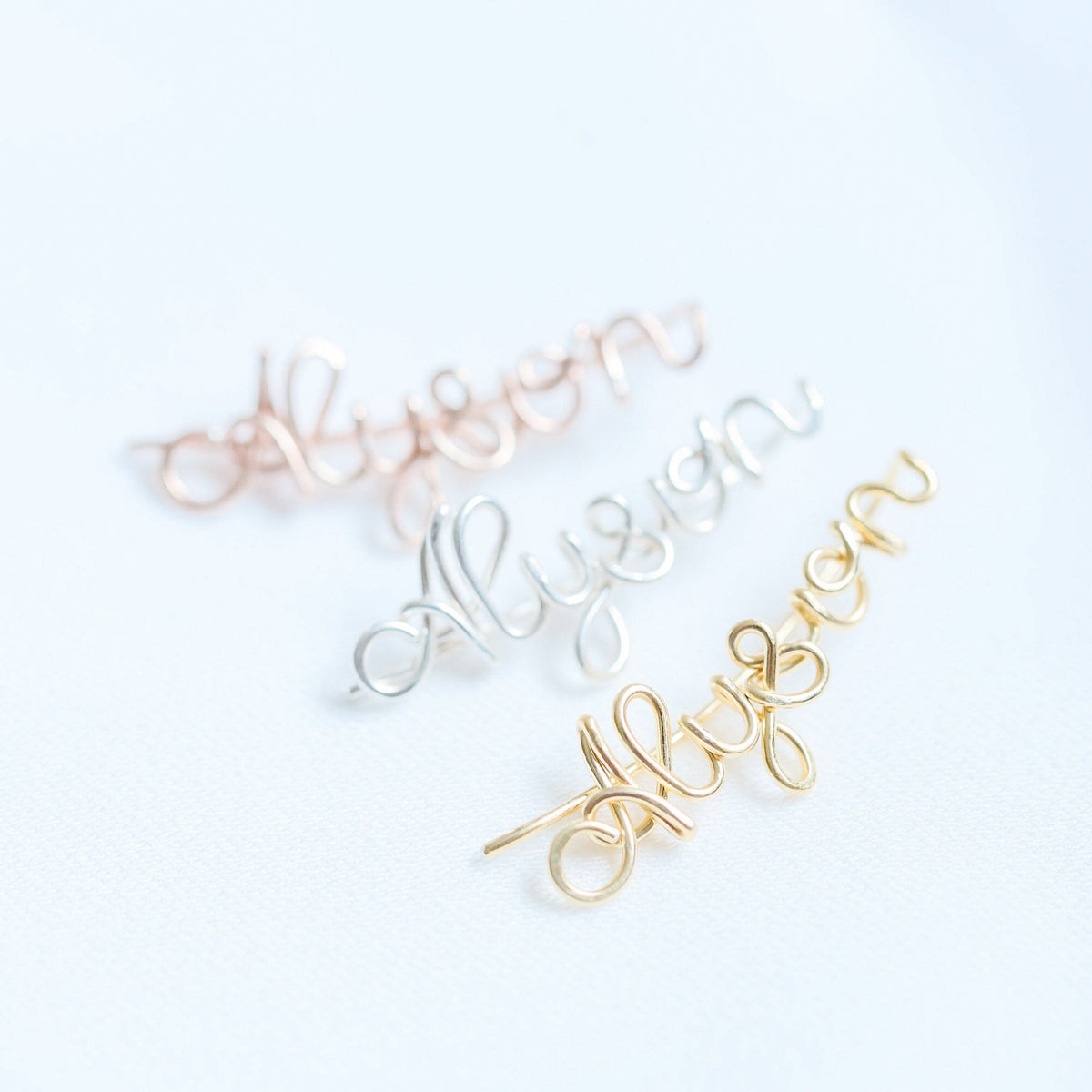 Handmade personalized name ear climber worn across the lobe through one standard piercing, featuring a custom flowing wire script design made with the chosen name or word up to 10 characters, available as a single left ear climber, single right ear climber or pair in solid 925 sterling silver, 14k gold filled and 14k rose gold filled.