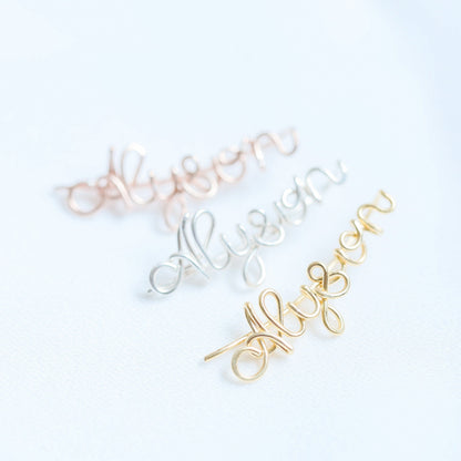 Handmade personalized name ear climber worn across the lobe through one standard piercing, featuring a custom flowing wire script design made with the chosen name or word up to 10 characters, available as a single left ear climber, single right ear climber or pair in solid 925 sterling silver, 14k gold filled and 14k rose gold filled.
