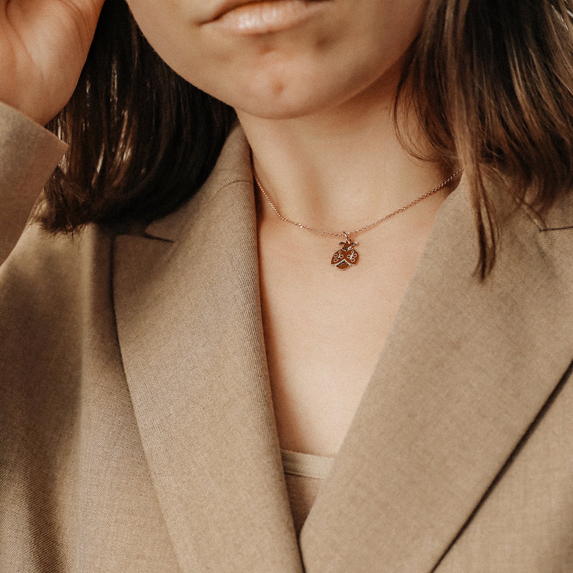 Ladybug necklace worn by model with beige blazer for elegant everyday styling
