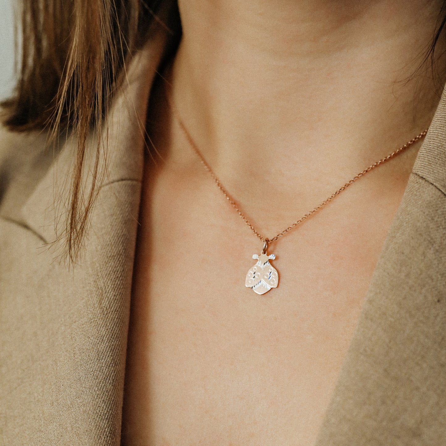 Ladybug necklace worn by model with beige blazer for elegant everyday styling