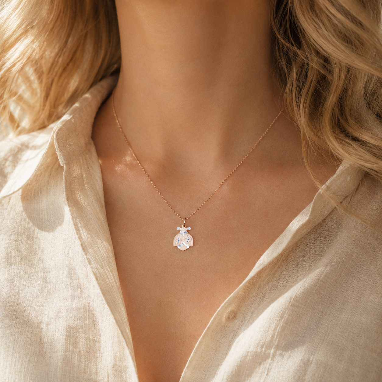 Ladybug necklace worn by model in warm golden hour light with cream shirt