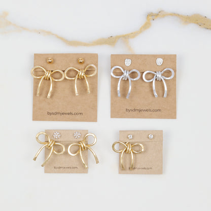Medium bow ear jackets shown in both gold and silver finishes on display cards, styled with different stud earring examples to show possible looks.