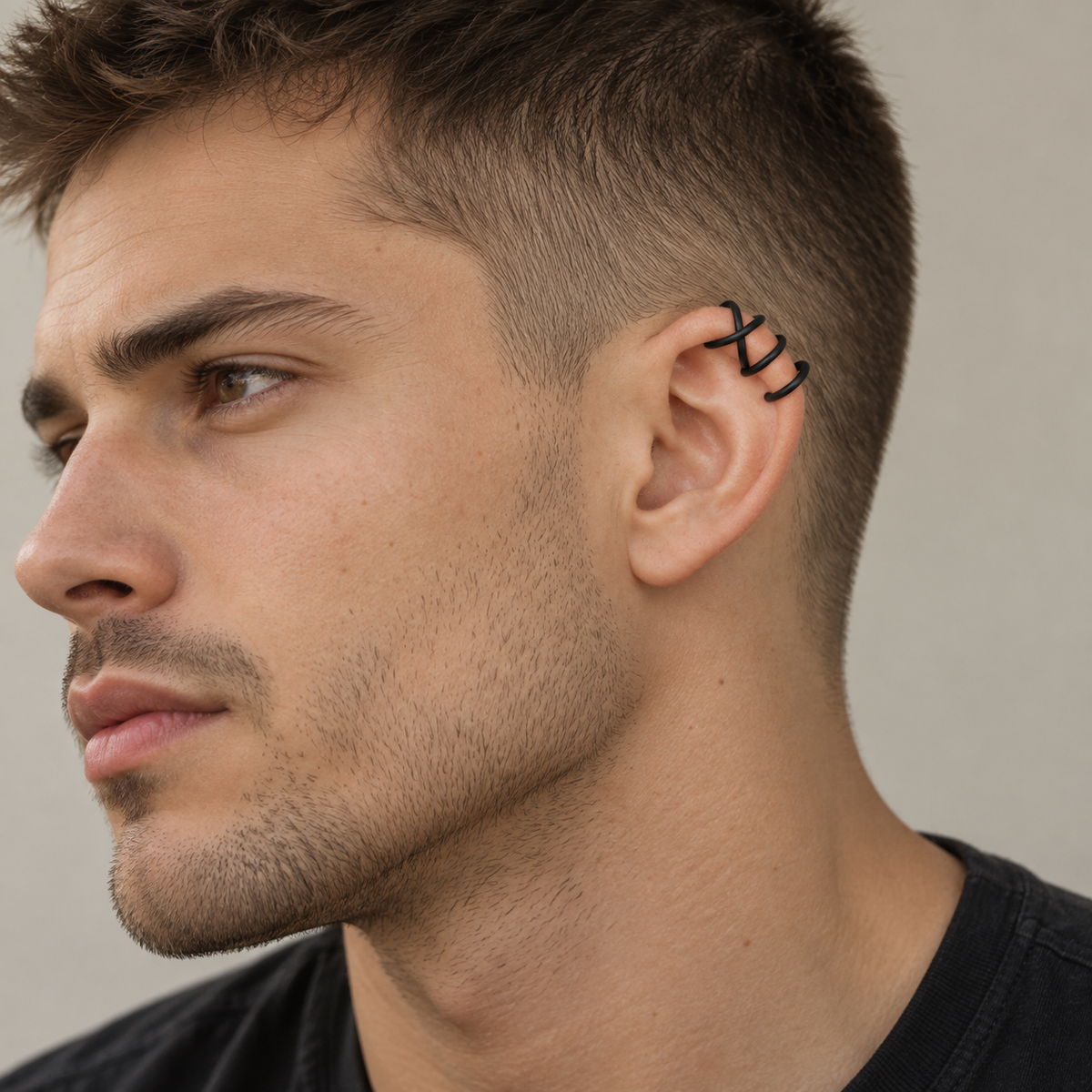 Black Criss-Cross helix ear cuff worn on the upper cartilage of a man, creating a bold minimalist ear detail without a piercing.