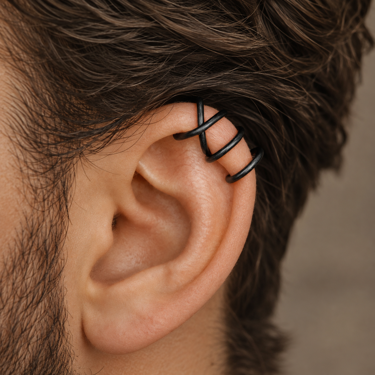 1. Macro close-up of a black Criss-Cross helix ear cuff on a man's cartilage, showing the bold smooth lines wrapping securely around the upper ear.