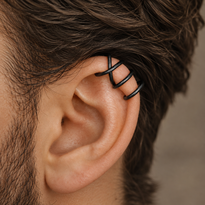 1. Macro close-up of a black Criss-Cross helix ear cuff on a man's cartilage, showing the bold smooth lines wrapping securely around the upper ear.