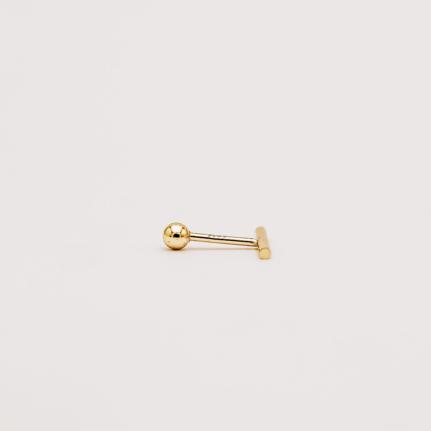 Close up of minimal bar screw back earring with polished gold finish