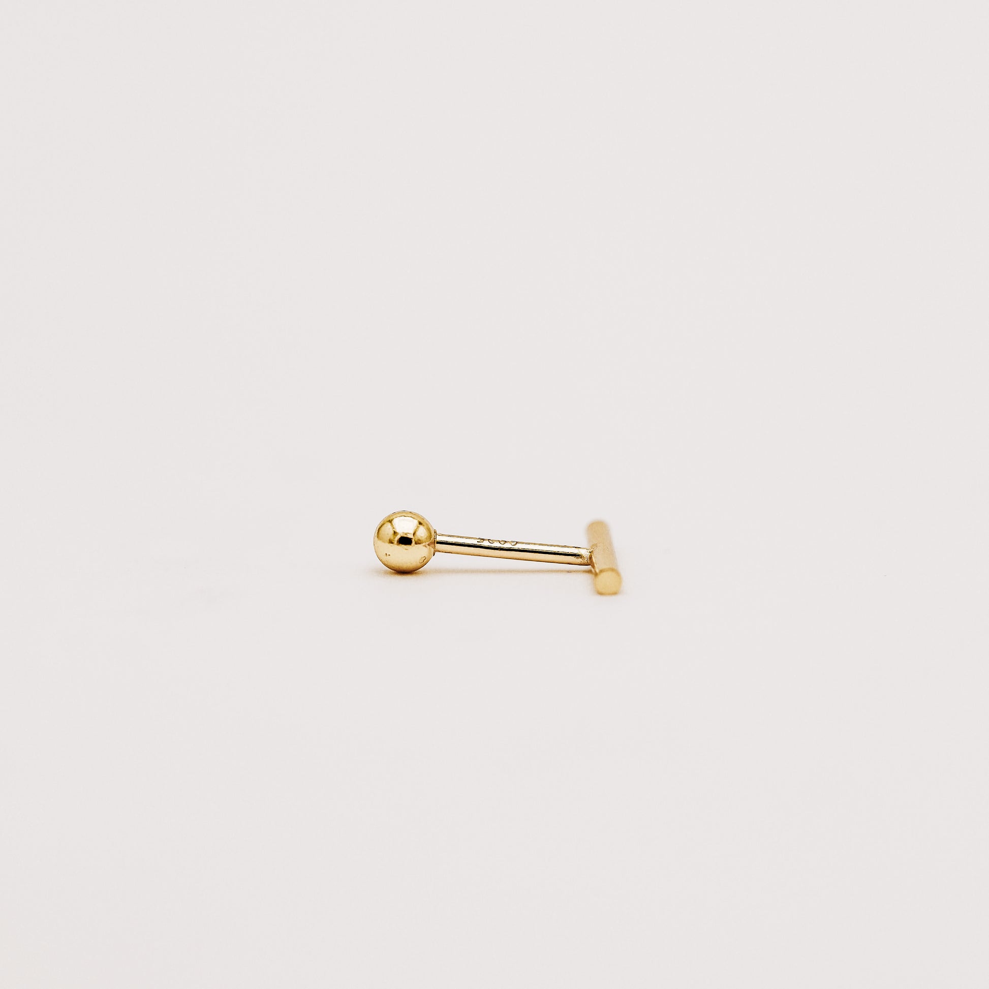 Close up of minimal bar screw back earring with polished gold finish