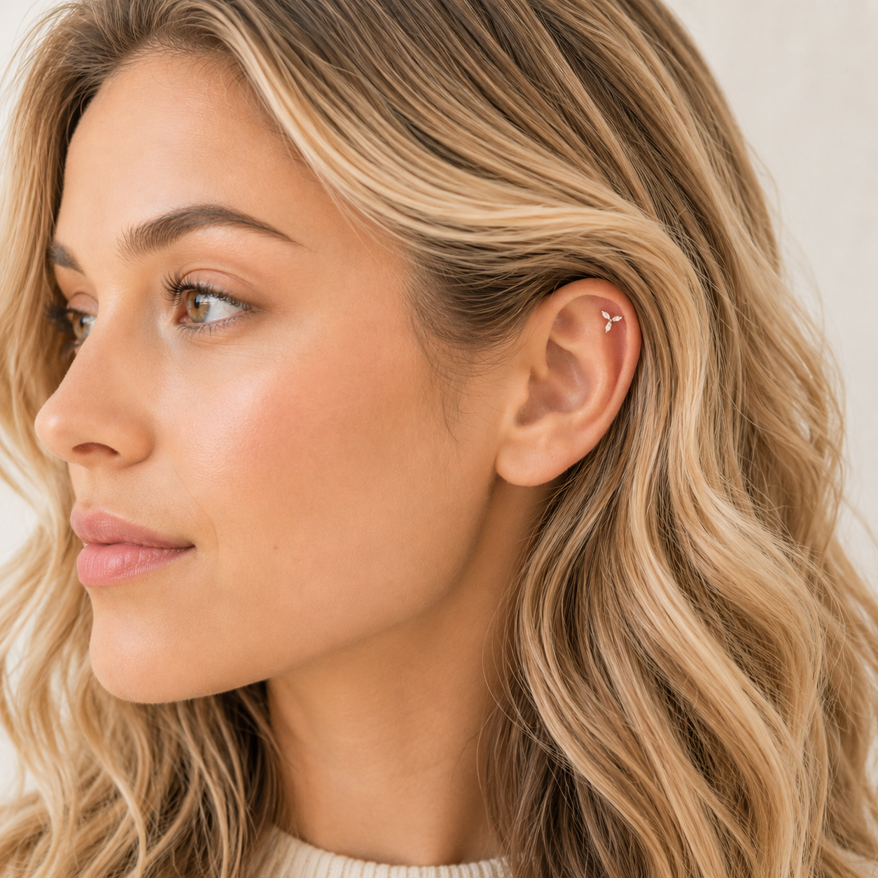 Close up of minimal gold bar screw back earring worn on upper ear with natural lighting, blonde wavy hair and detailed helix piercing view.