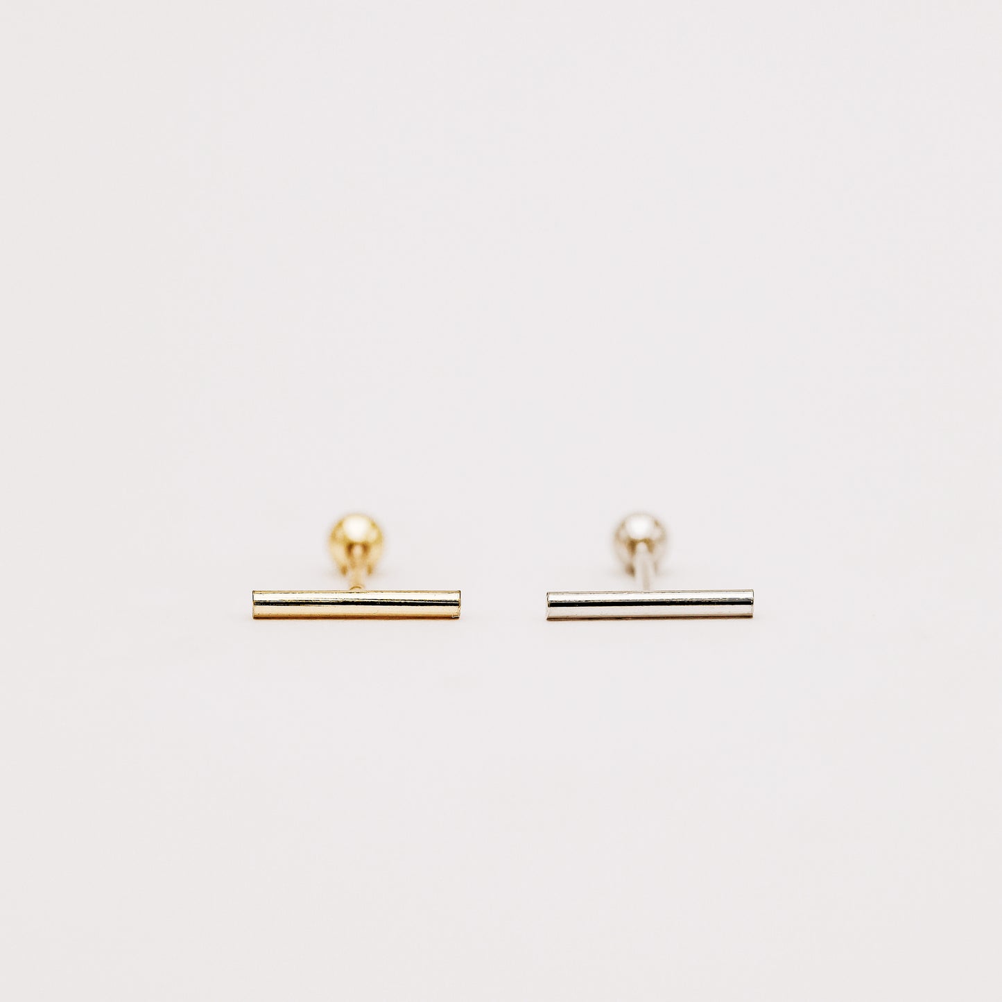 Minimalist bar earring worn on lobe piercing close up