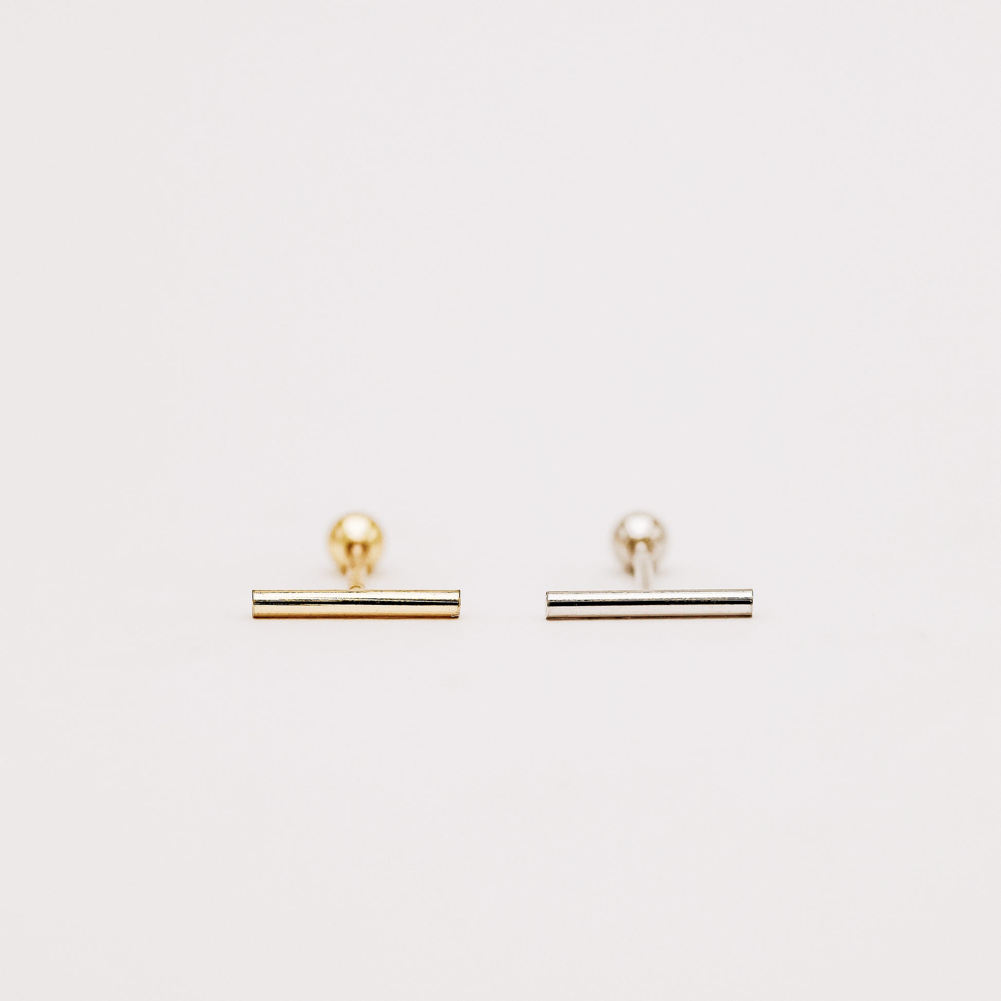 Minimalist bar earring worn on lobe piercing close up